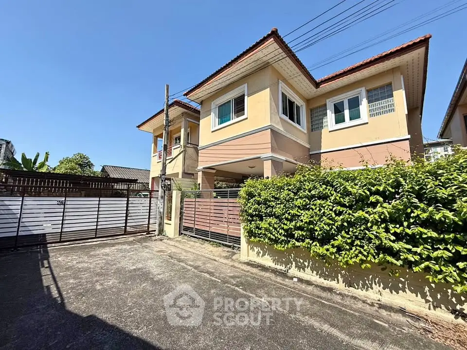 Charming two-story house with lush greenery and spacious driveway in a serene neighborhood.