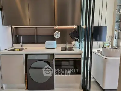 Modern kitchen with sleek appliances and open layout adjacent to cozy living area.