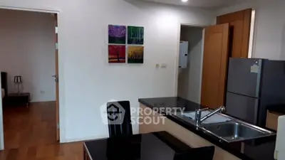 Modern kitchen with sleek black countertops and stainless steel fridge in a cozy apartment setting.