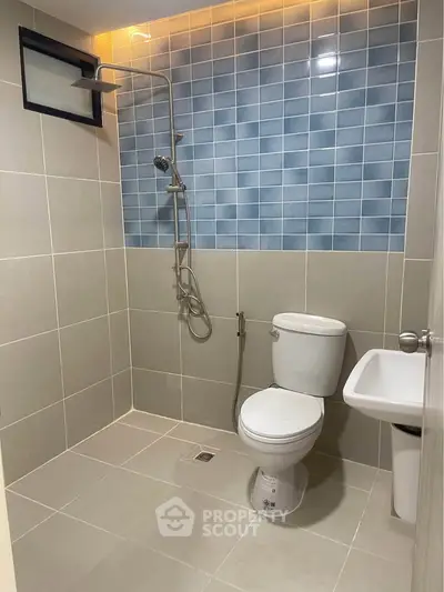 Modern bathroom with sleek shower and stylish blue tile accent wall.