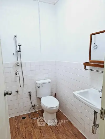 Compact bathroom with modern fixtures and wooden flooring, ideal for small spaces.