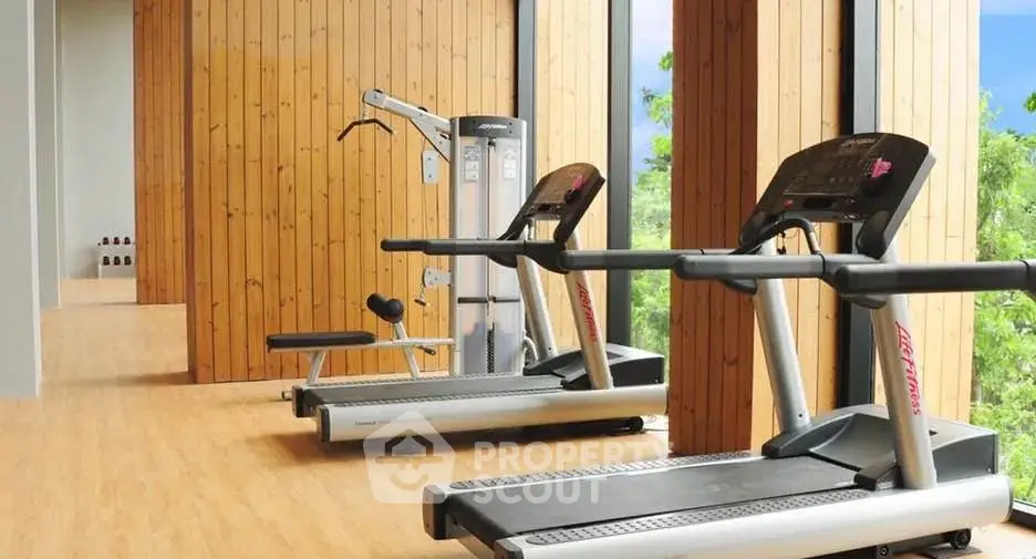 Modern gym with treadmills and weight machines in a stylish wooden interior
