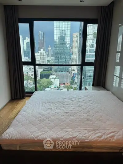 Modern bedroom with stunning city view through large windows in high-rise apartment.