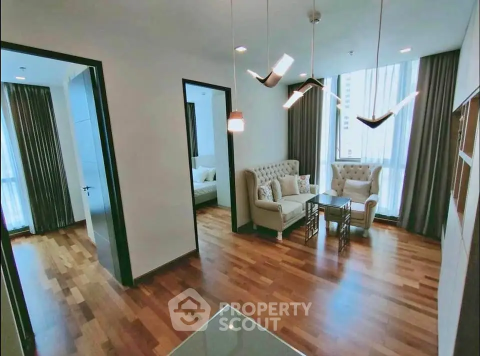 Elegant living room with modern lighting and hardwood floors in a stylish apartment.
