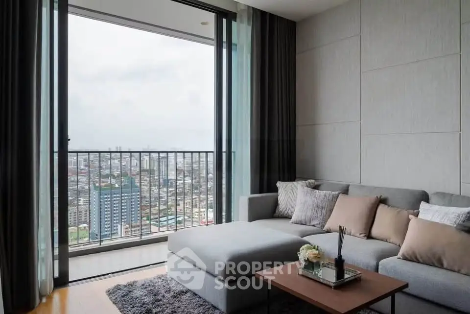 Modern living room with stunning city view from large balcony, featuring cozy gray sectional sofa and elegant decor.