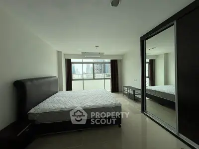 Spacious bedroom with city view and mirrored wardrobe in modern apartment.