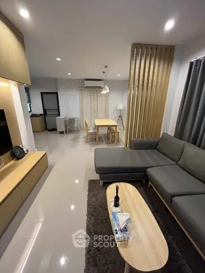 Modern living room with sleek furniture and open dining area, perfect for contemporary living.