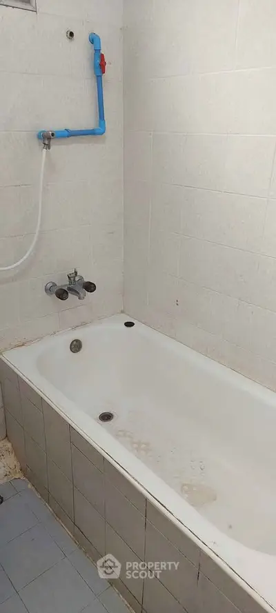 Simple bathroom with bathtub and tiled walls, ideal for renovation.