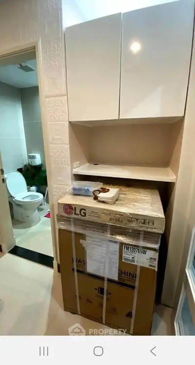 Compact bathroom with modern washing machine and sleek storage cabinets.