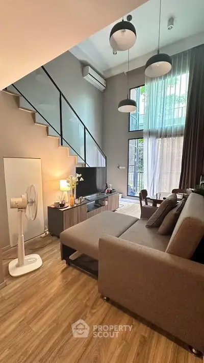 Modern living room with high ceilings, stylish decor, and large windows for natural light.