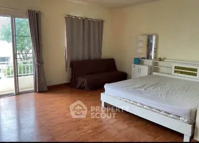 Spacious bedroom with wooden flooring and balcony access in modern apartment.
