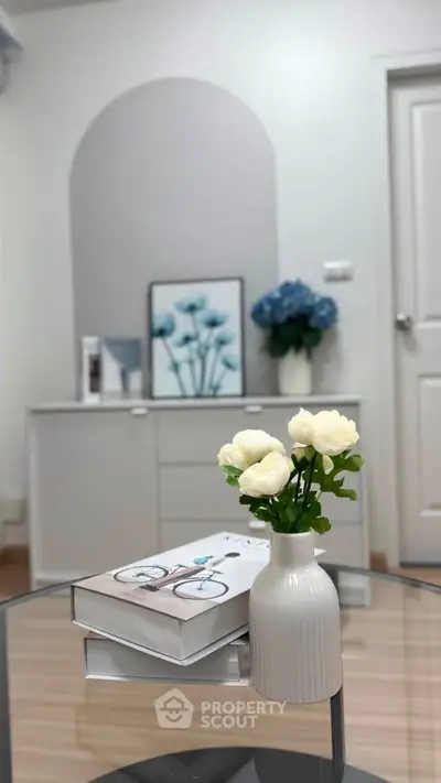 Stylish modern interior with elegant decor and fresh flowers on a glass table, creating a welcoming ambiance.