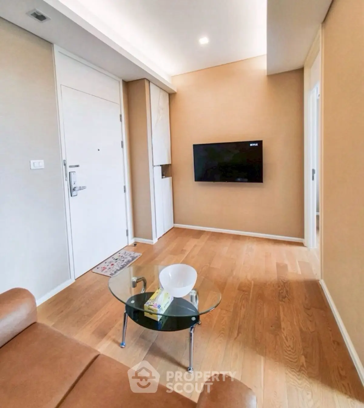 Modern living room with wooden flooring, wall-mounted TV, and stylish furniture.