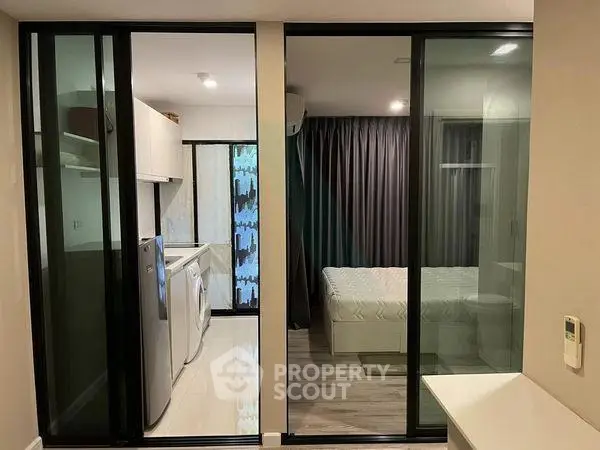 Modern apartment interior with sliding glass doors, compact kitchen, and cozy bedroom.