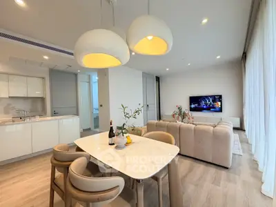 Modern open-plan living room with elegant dining area and cozy seating, featuring stylish lighting and contemporary decor.