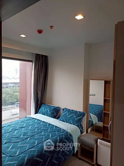 Cozy bedroom with large window and modern decor, perfect for urban living.