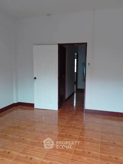 Spacious empty room with wooden flooring and white walls, perfect for customization.