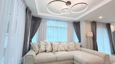Luxurious living room with modern lighting and elegant curtains, featuring a plush sectional sofa.
