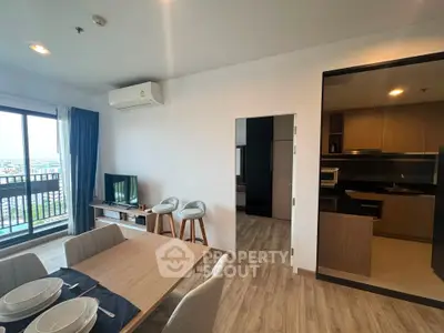 Modern open-plan living room with dining area and kitchen, featuring stylish decor and natural light.