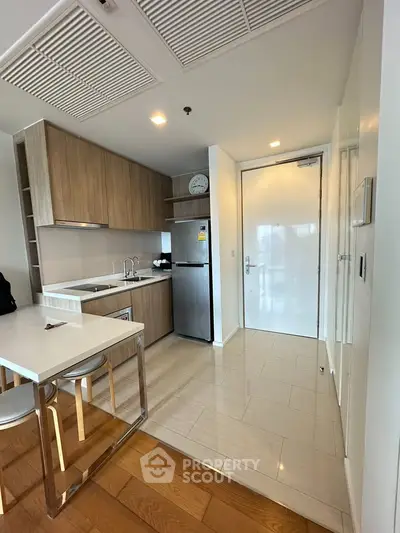 Modern kitchen with sleek wooden cabinets and stainless steel appliances in a stylish apartment.