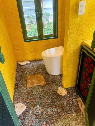 Unique colorful bathroom with vibrant yellow walls and artistic flooring