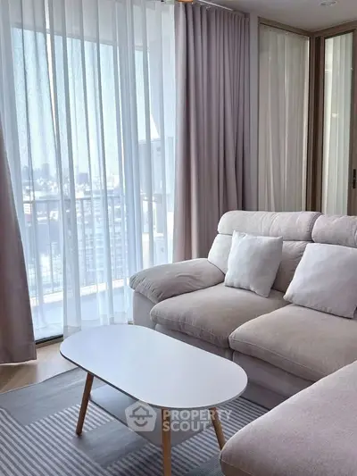 Bright and cozy living room with modern furniture and large windows offering city views.