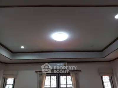 Spacious room with modern ceiling light and air conditioning, featuring elegant window drapes.