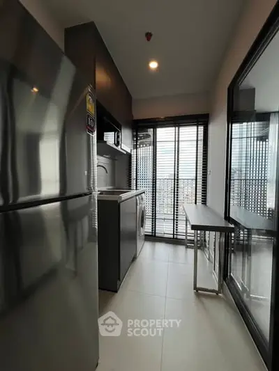 Modern kitchen with sleek appliances and balcony view in urban apartment