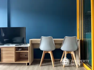 Modern living room with stylish furniture and TV setup, featuring a sleek wooden desk and chairs.