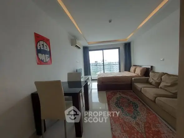 Modern studio apartment with cozy bed, stylish sofa, and work desk, featuring a large window with city view.