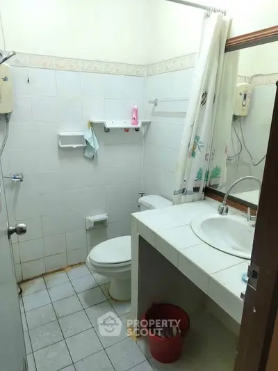 Compact bathroom with tiled walls and essential fixtures, ideal for small spaces.