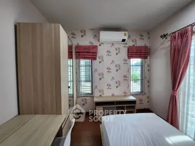Charming bedroom with floral wallpaper, wooden furniture, and natural light from large windows.