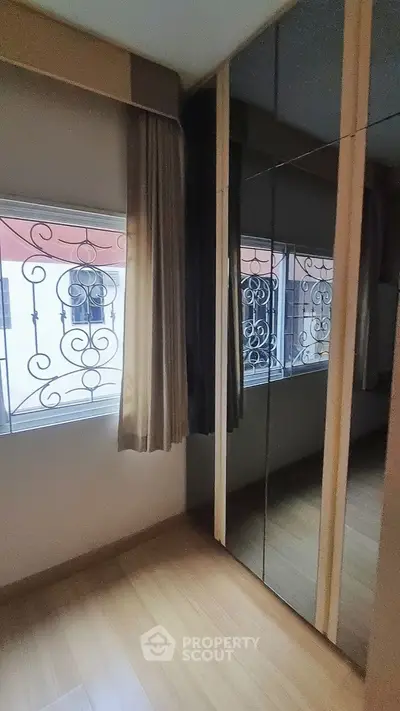 Elegant mirrored wardrobe in a cozy bedroom with decorative window grills.