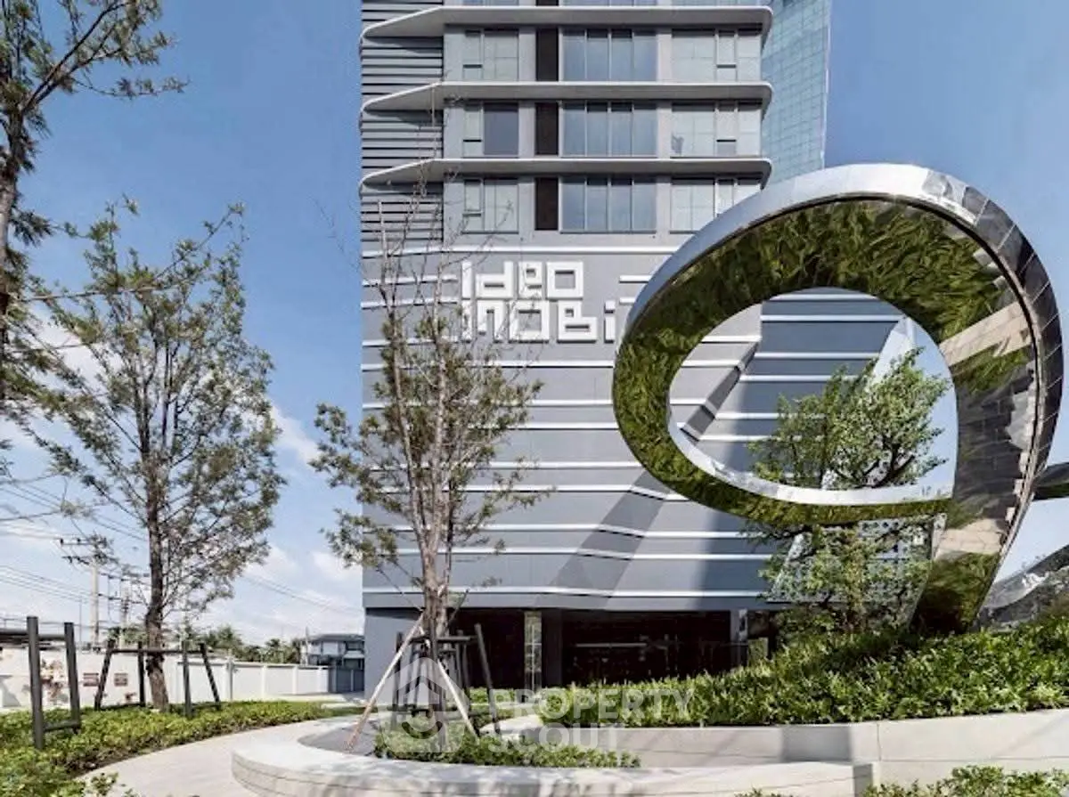 Modern high-rise building with unique architectural design and lush landscaping.