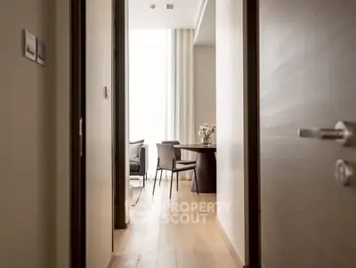 Modern apartment hallway leading to a cozy living area with elegant furniture and natural light.