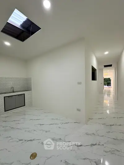 Spacious modern hallway with marble flooring and sleek kitchenette