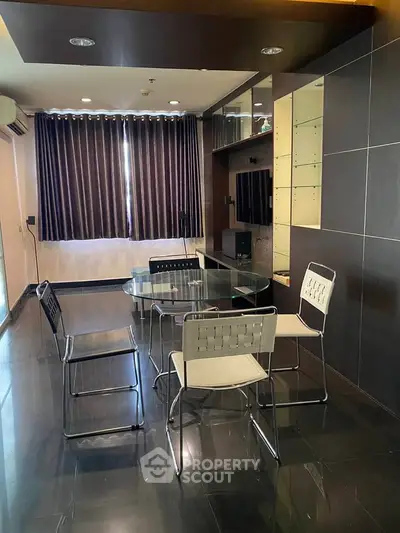 Modern living room with sleek furniture and glass table, featuring dark curtains and polished flooring.