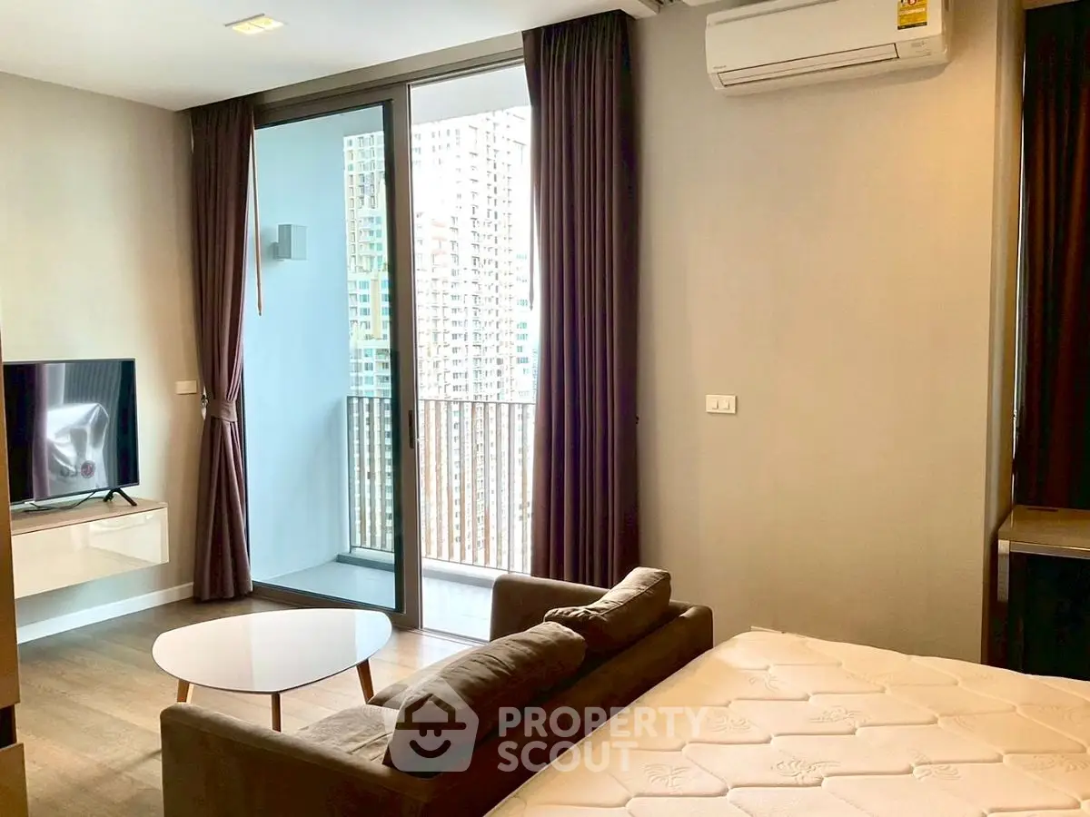 Modern studio apartment with balcony and city view, featuring sleek furniture and natural light.