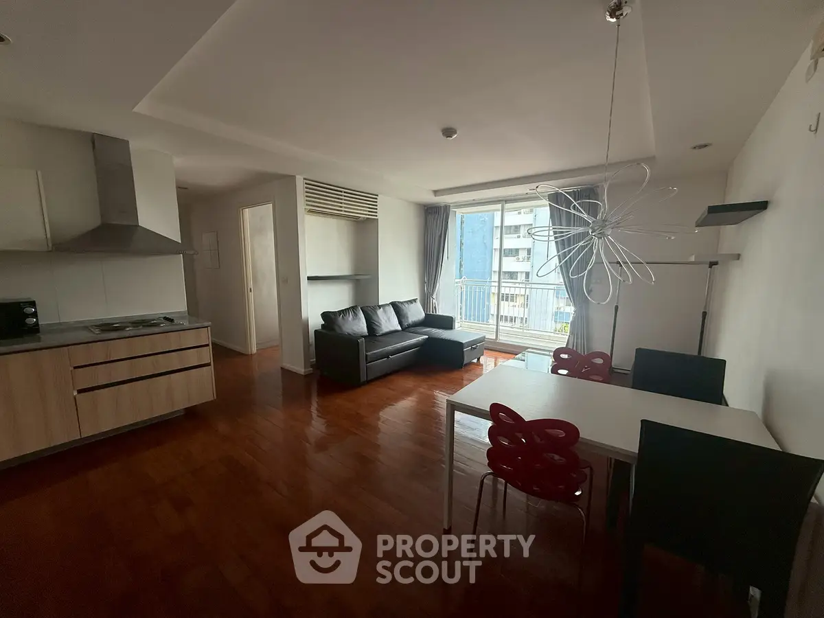 Spacious modern living room with open kitchen and balcony view in urban apartment.