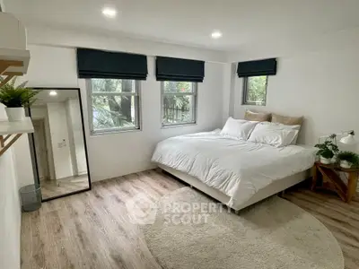 Spacious bedroom with large windows and modern decor in a serene setting.