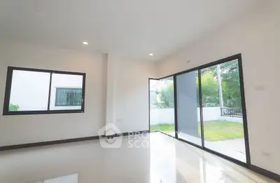 Spacious living room with large windows and garden view, perfect for natural light lovers.