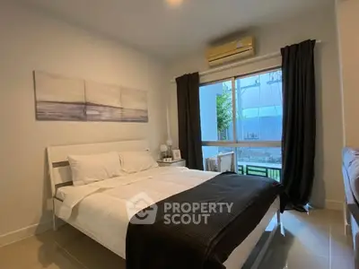 Cozy bedroom with modern decor and large window offering natural light.