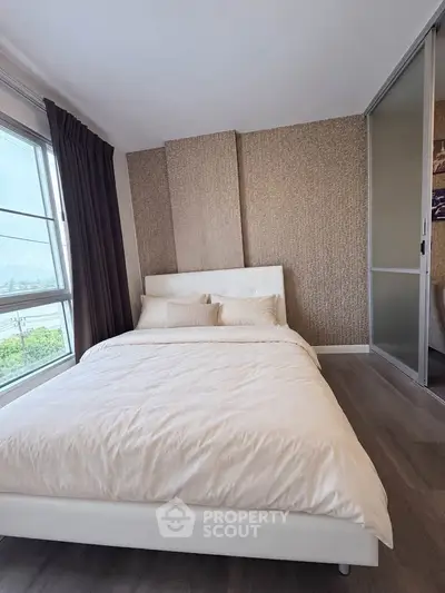 Modern bedroom with stylish decor and large window offering natural light.