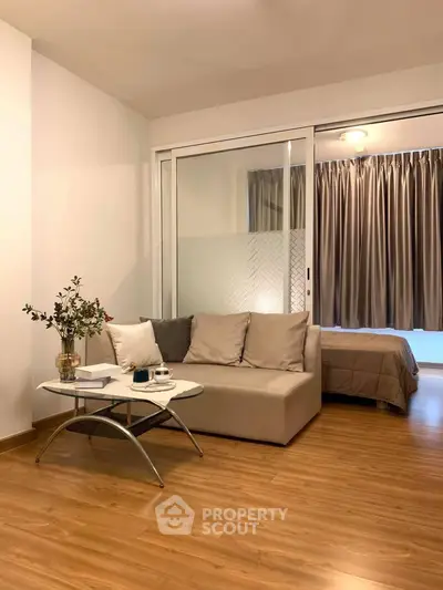 Modern studio apartment with cozy living area and bedroom separated by sliding glass doors.