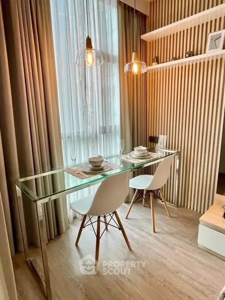 Modern dining area with glass table and stylish lighting in cozy apartment.