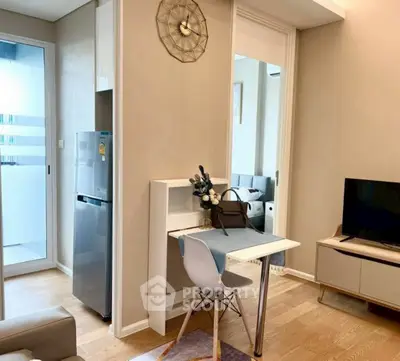 Modern living room with stylish decor and compact dining area, featuring a sleek refrigerator and wall-mounted TV.
