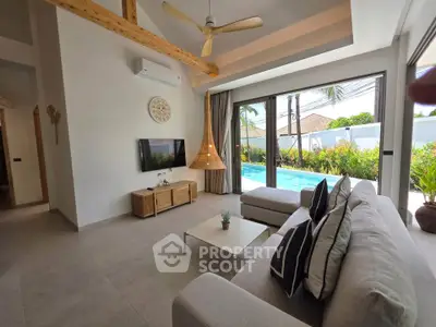 Luxurious living room with pool view, modern decor, and natural light in a tropical villa.