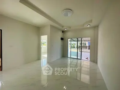 Spacious modern living room with large windows and marble flooring, offering ample natural light and outdoor access.