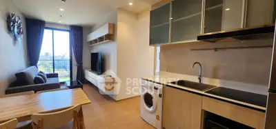 Modern open-plan living room and kitchen with city view, featuring sleek furniture and built-in appliances.