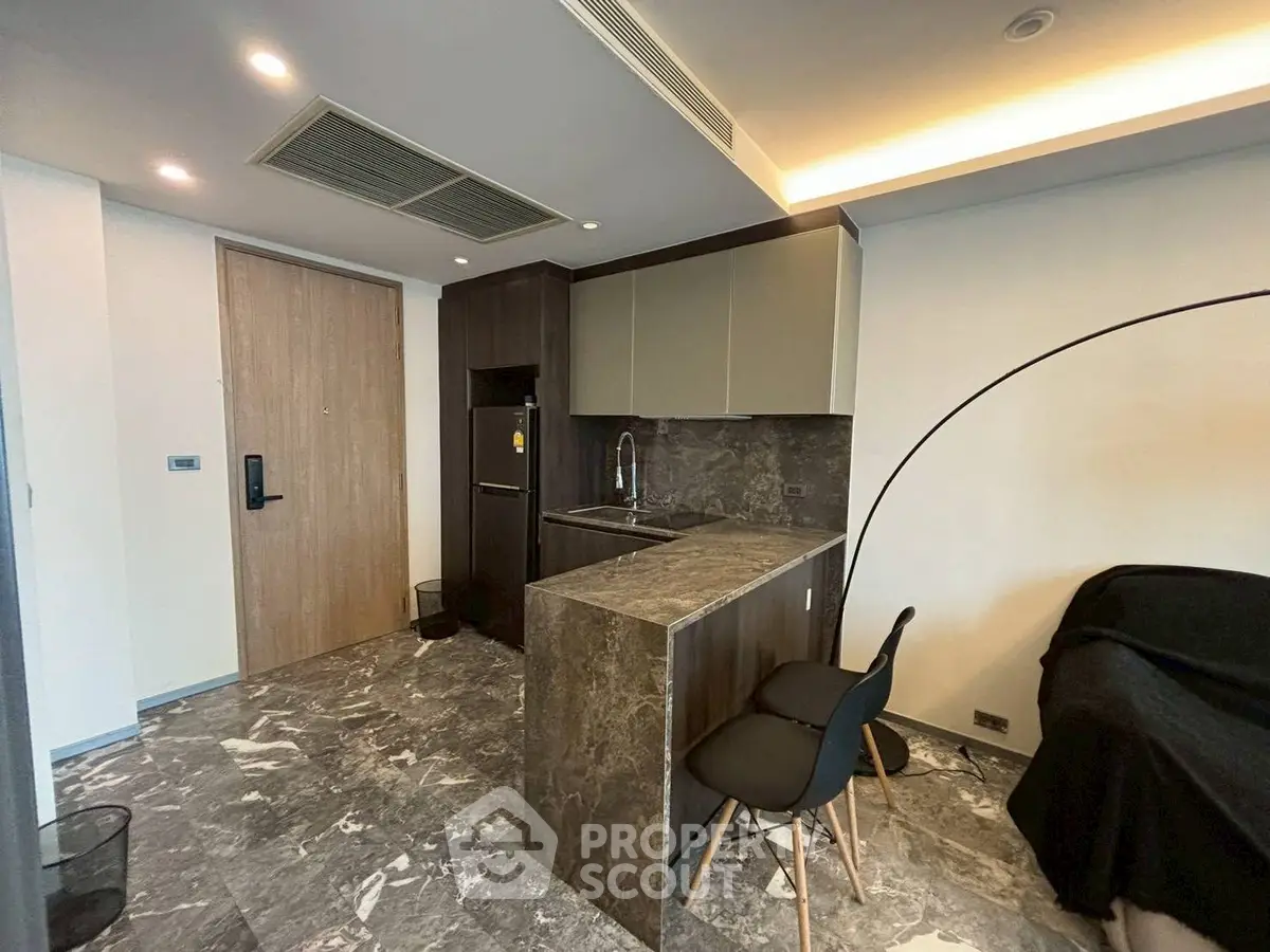 Modern kitchen with sleek design, marble flooring, and stylish seating in a contemporary apartment.